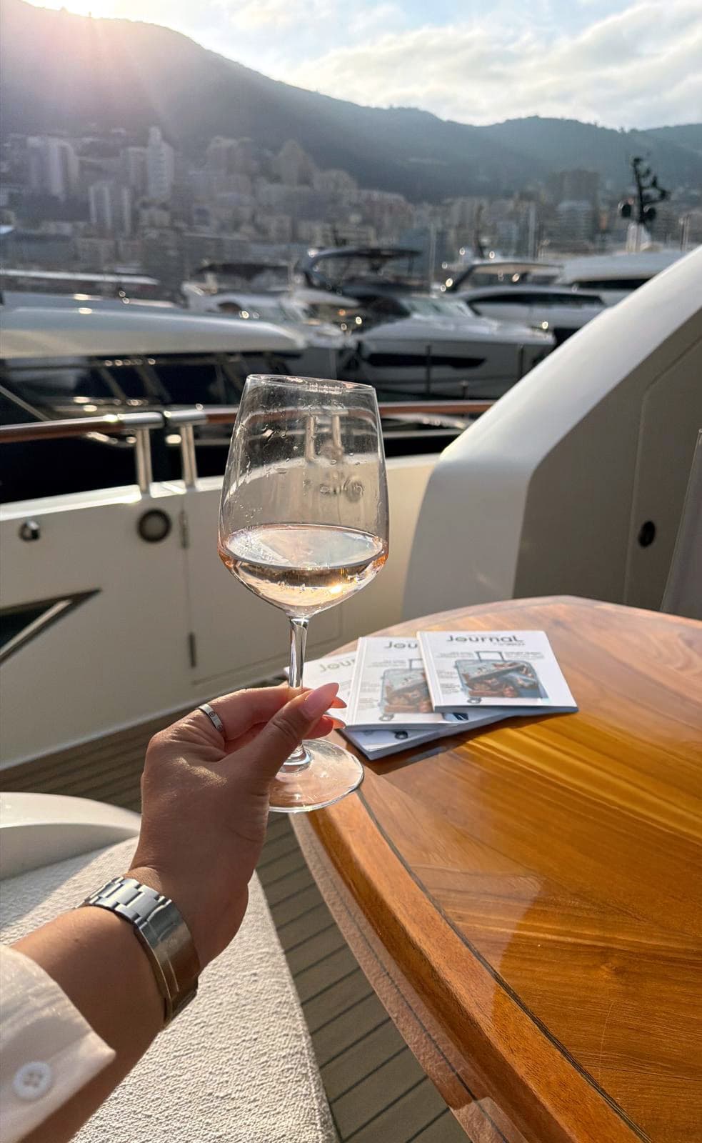 A glass of rosé on the aft deck overlooking Monaco at golden hour